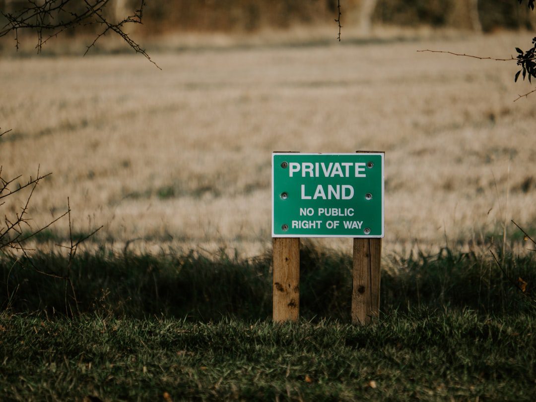 A land for sale sign on an open plot, representing land banking
